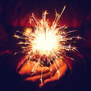 Two hands holding a lit sparker