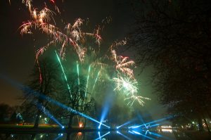 Lights and professional fireworks reflected over a river